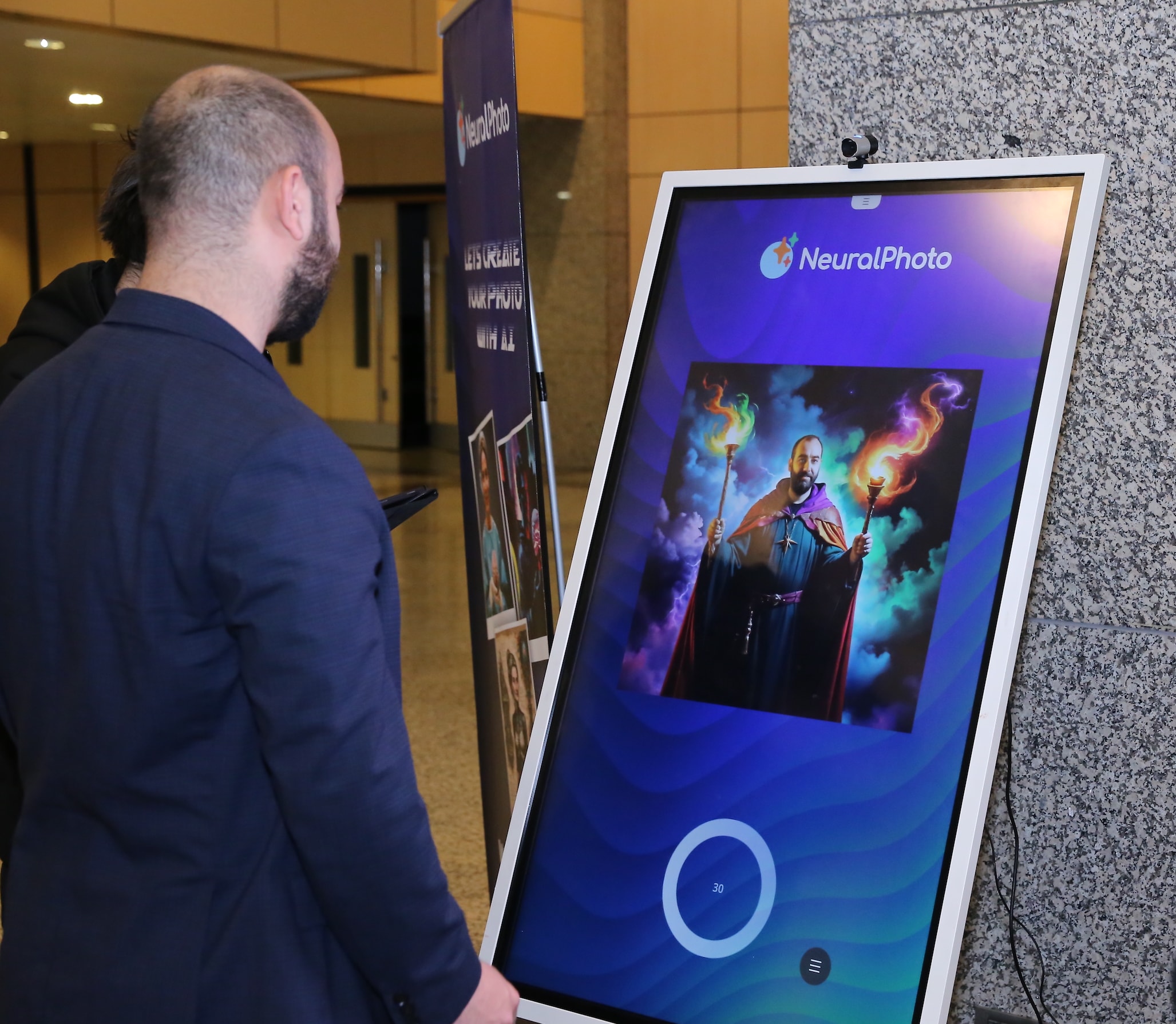 Participant using the NeuralPhoto AI photo kiosk at WLNC 2024, generating a themed portrait with fantasy effects on a touchscreen display.
